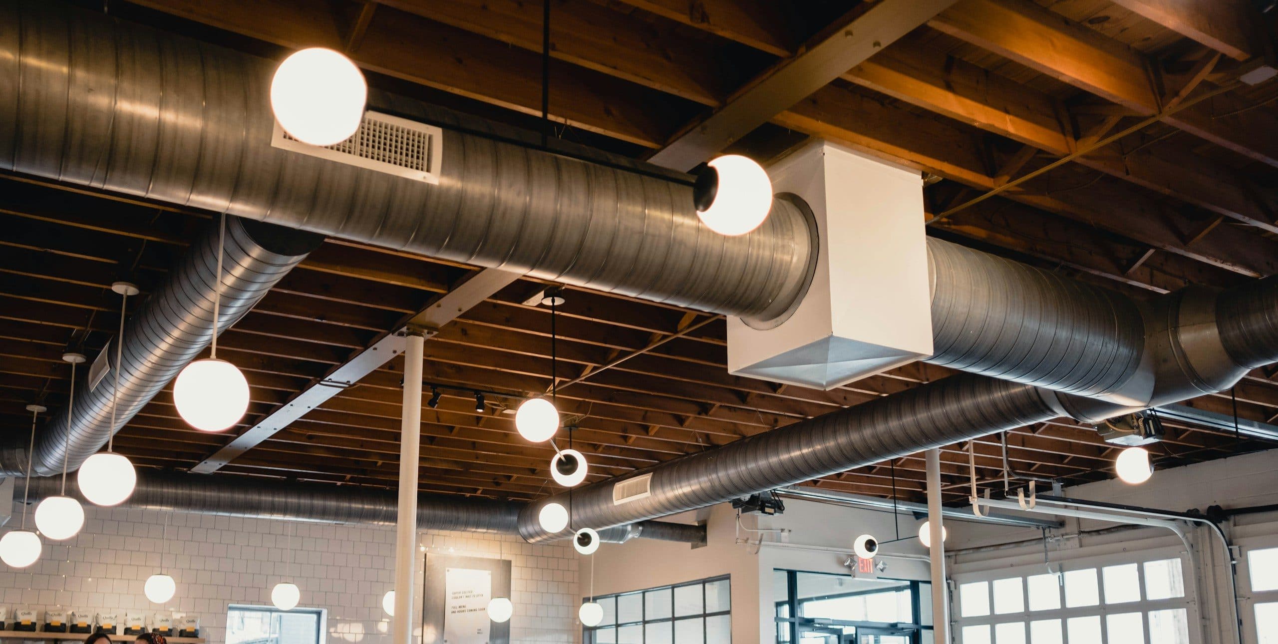Spiraalvormige ventilatiekanalen onder een houten plafond met bolvormige lampen